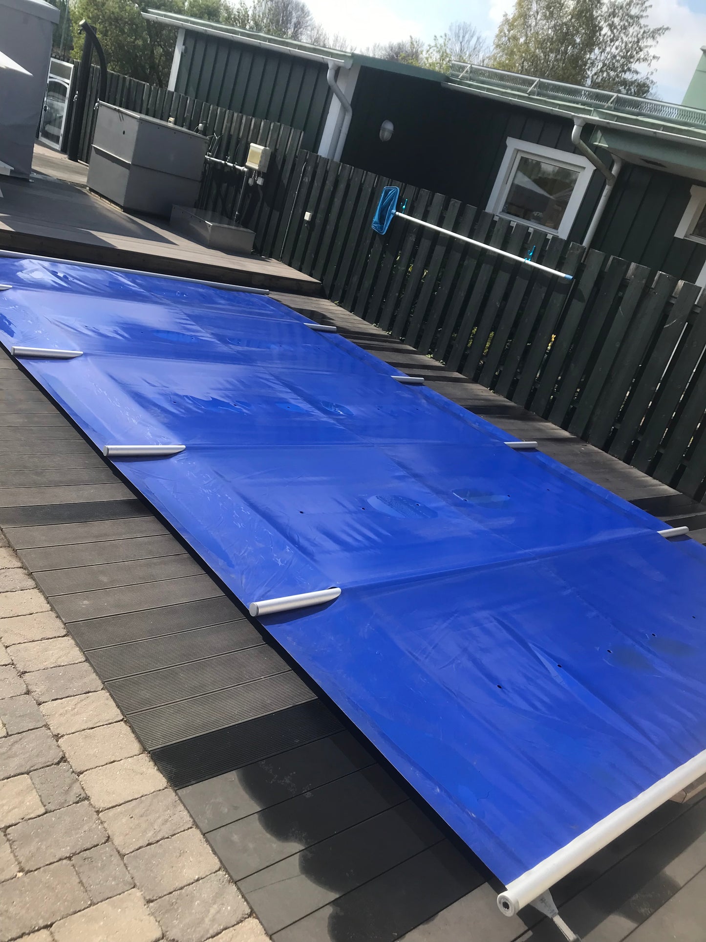 Blå Rib-Cover poolskydd utrullat på trädäck före installation