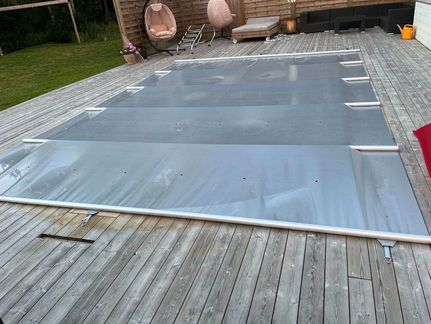 Grått Rib-Cover poolskydd över pool med regnvatten på skyddets yta