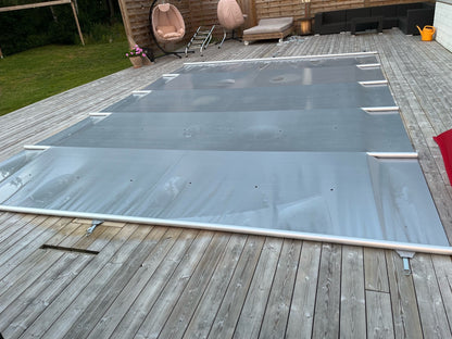 Grått Rib-Cover poolskydd över pool med regnvatten på skyddets yta