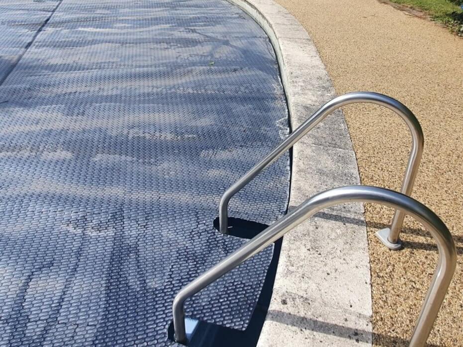 GeoBubble solfolie över pool vid rostfri poolstege och betongkant